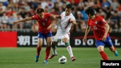 Iran's Masoud Shojaei (center) challenges South Korea's Lee Myoung-ju (left) and Kim Chang-soo during their World Cup qualifying soccer match in Ulsan.