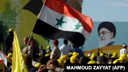 File photo - Lebanese Hezbollah supporters wave a Syrian flag under a huge portrait of Iran's supreme leader, Ayatollah Ali Khamenei, during a rally in the southern town of Bint Jbeil on May 25, 2012.