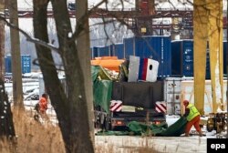 Ukrainian workers load parts of the wreckage of MH17 on trucks at a terminal in Kharkiv on December 3.