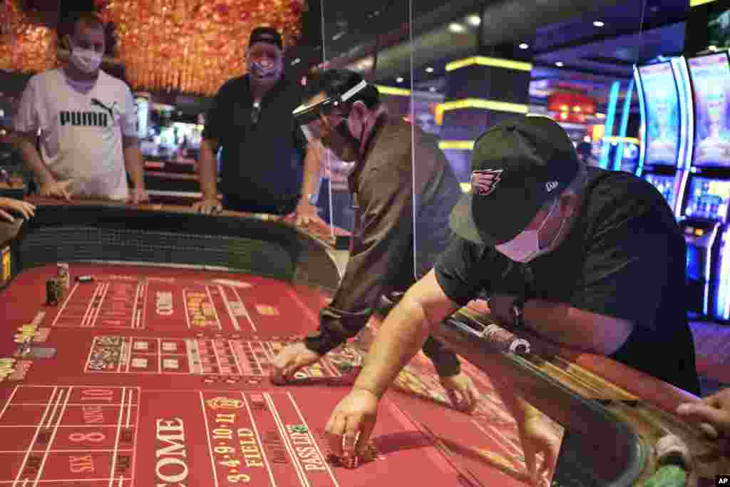 Игроки и работники казино Golden Nugget в Атлантик-Сити, штат Нью-Джерси. Все желающие попасть в заведение с игровыми автоматами и рулетками после 108-дневного карантина обязаны надевать защитные маски
