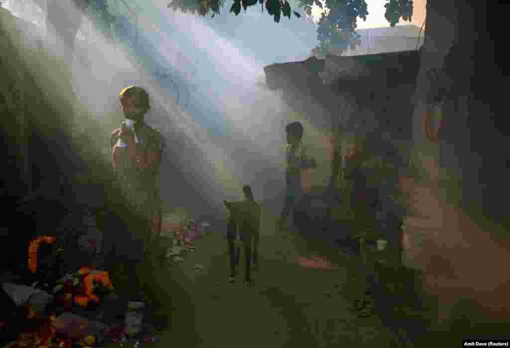 A girl stands outside her house as a health worker fumigates a residential area to prevent the spread of mosquito-borne diseases in Ahmedabad, India. (Reuters/Amit Dave)