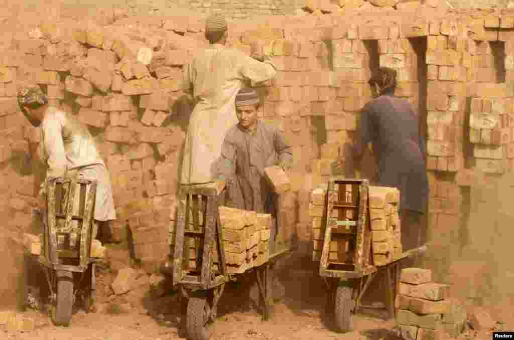 Laborers move bricks from an oven at a kiln on the outskirts of Peshawar, Pakistan. (Reuters/Fayaz Aziz)