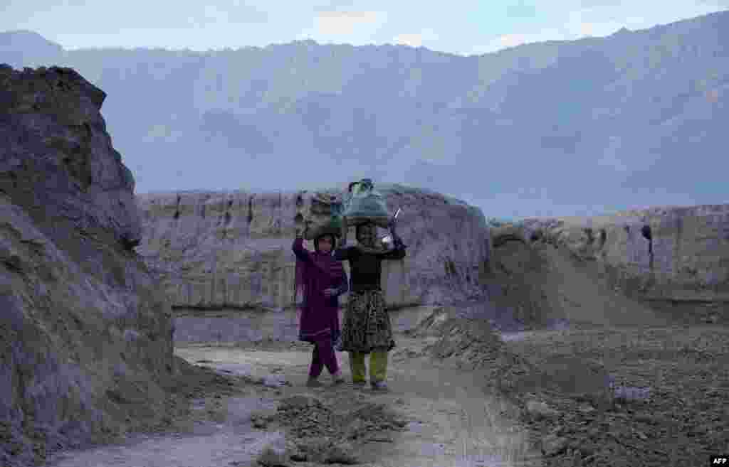 Afghan girls carry bags of coal to use as fuel in their homes as the winter sets in on the outskirts of Jalalabad. (AFP/Noorullah Shirzada)