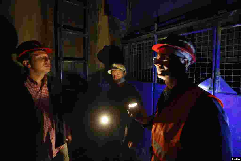 Serbian miners use flashlights in an elevator as they descend into the copper mine.
