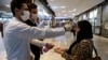 A woman has her temperature checked and her hands disinfected as she enters the Palladium Shopping Center, in northern Tehran, March 3, 2020