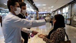 Iran -- A woman has her temperature checked and her hands disinfected as she enters the Palladium Shopping Center in Tehran, March 3, 2020