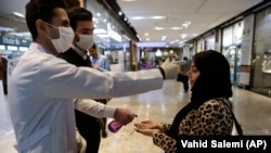 A woman has her temperature checked and her hands disinfected as she enters the Palladium Shopping Center, in northern Tehran, March 3, 2020