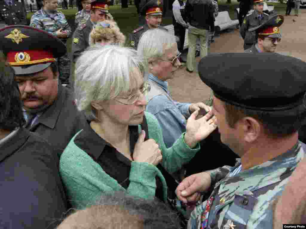 Russia - Photo exibition of Dmitry Borko in RFE/RL office, Prague. Journalist Anna Politkovskaya is surrounded by police during a banned rally in Moscow less than two months before she was murdered. 19 August 2006. - Anna Politkovskayanı Rusiädä sosial ğadelsezlek häm keşe xoquqlarınıñ bozıluına qarşı köräşüçe bularaq belälär ide. Azatlıq radiosı fotorässamı Dmitry Borko bu räsemne Mäskäwdä uram cıyınında yasadı. İke aydan Politkovskaya atıp üterelde.