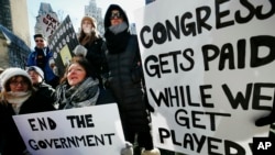 U.S. government workers and their supporters hold signs during a protest in Boston, Friday, Jan.11, 2019