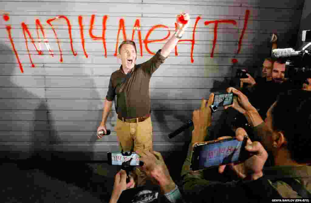 A protester gestures after writing &quot;Impeachment&quot; on a wall during a demonstration outside the Ukrainian presidential residence near Kyiv on September 10. (epa-EFE/Sergey Dolzhenko)