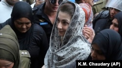 Police officers escort Maryam Nawaz as she appears at a court in Lahore in August.