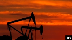 U.S. -- A file photograph showing pumping units sihouetted against a setting sun work continuously in an oil field near Los Angeles, California USA 11 March 2008.