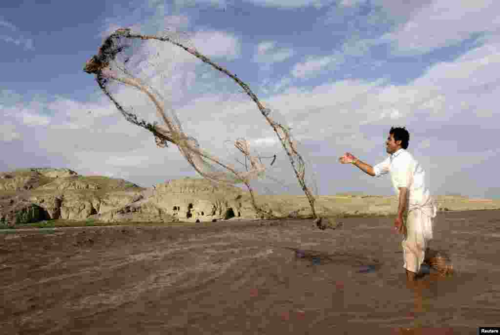 An Afghan man fishes with a net in a river on the outskirts of Jalalabad Province on May 19. (Reuters/Parwiz)