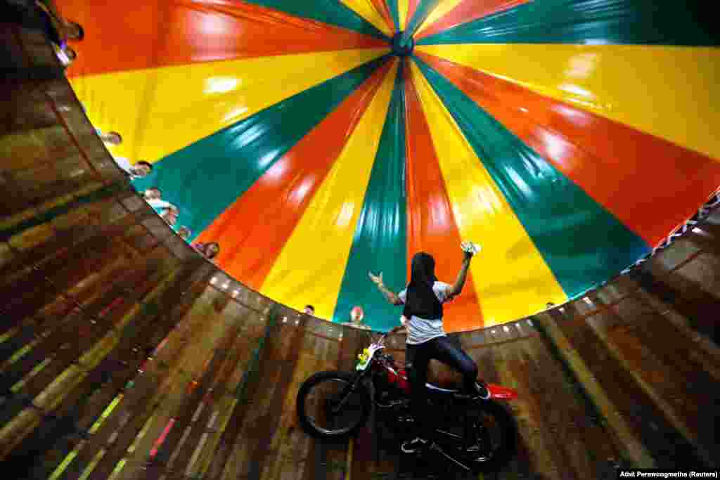 A stuntman with his face covered rides a motorcycle inside the &quot;Well of Death&quot; attraction during a fair in Bangkok, Thailand. (Reuters/Athit Perawongmetha)
