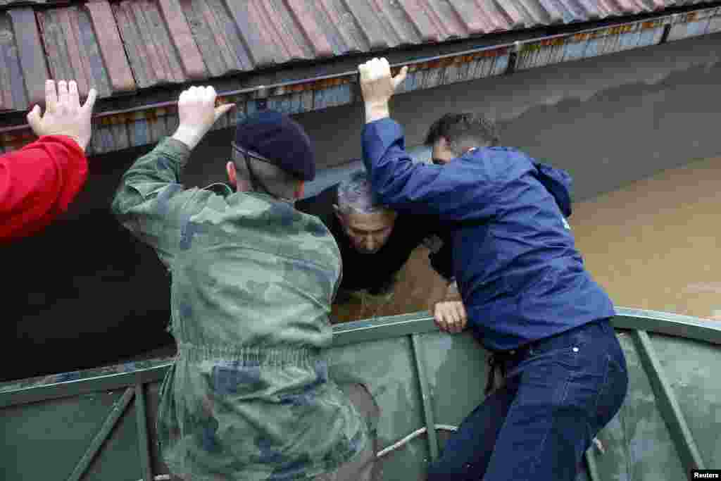 Serbian soldiers help a man out of his flooded house in the town of Obrenovac, Serbia.