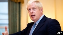 Britain's Prime Minister Boris Johnson gestures as he speaks to members of Britain's military during a reception for the Armed Forces inside 10 Downing Street in Central London on September 18, 2019. 