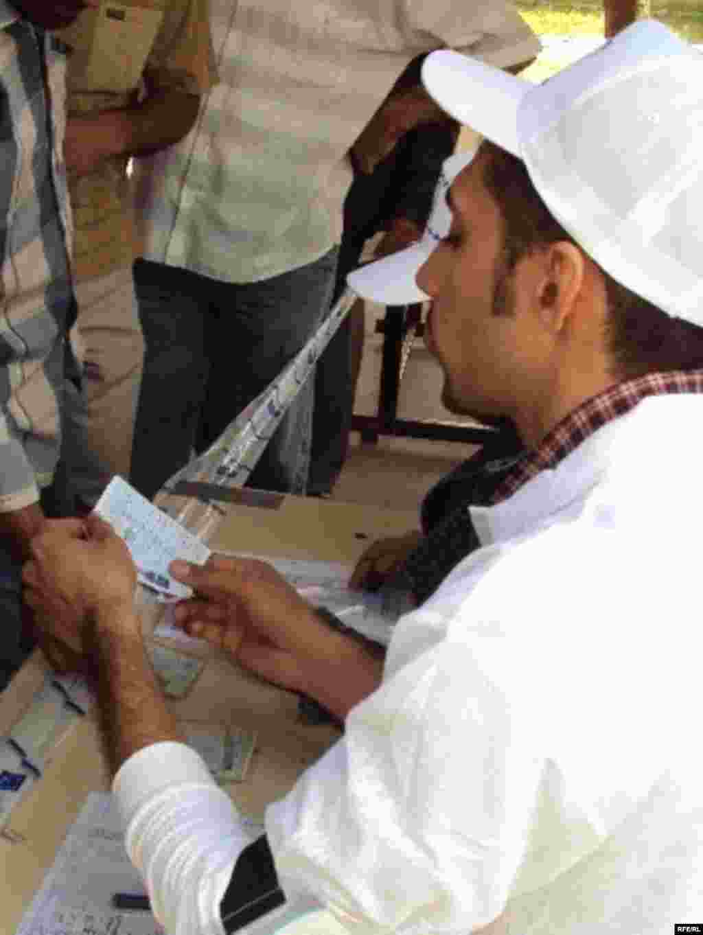 Election staff in Baghdad check the name of a voter against the official registry. (Photo: Radio Free Iraq)