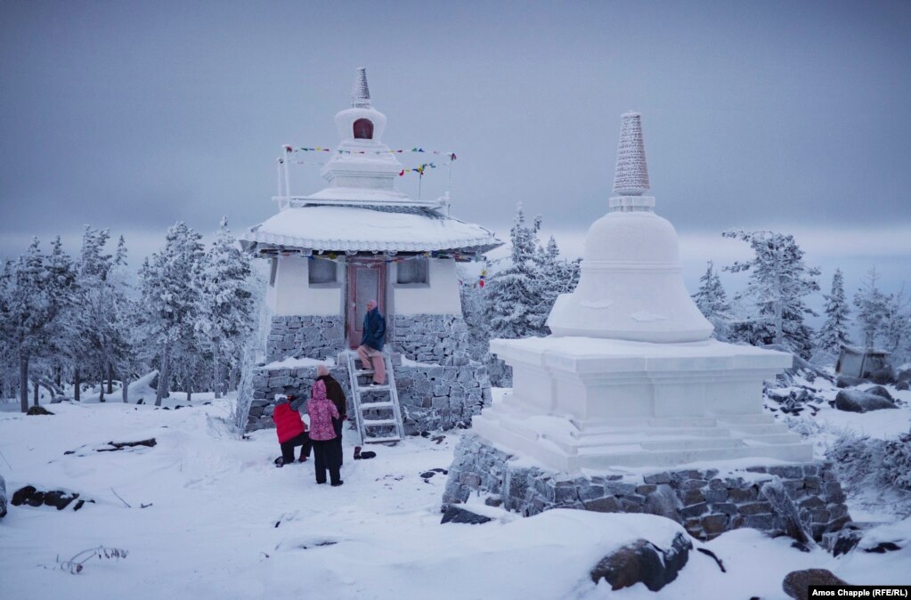 A group of tourists pose for photos at a stupa that is part of the monastery complex.