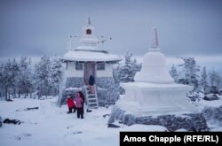 A group of tourists pose for photos at a stupa that is part of the monastery complex.