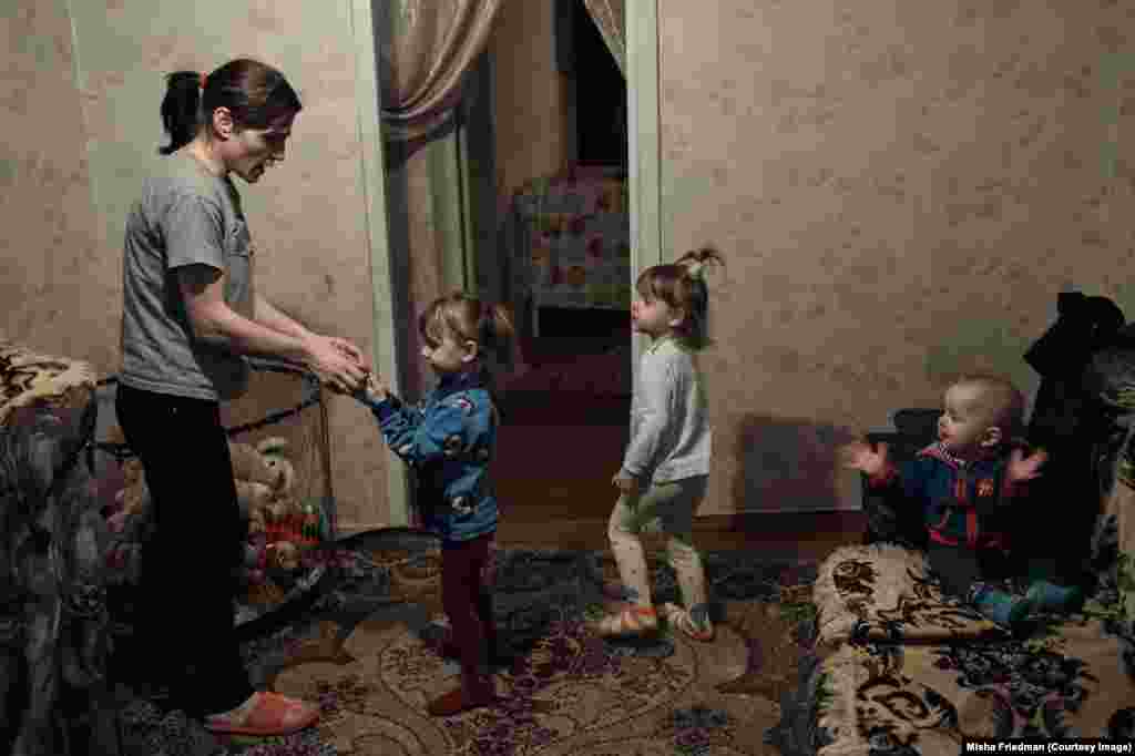 Tetyana, 33, with her three children. She contracted HIV from her husband, who was a drug user and died of complications from AIDS in January 2016. The family had fled its home during heavy fighting and Tetyana now lives in Kramatorsk, supported solely by NGOs and church groups. She is unable to work, as she is the only caregiver for her children.