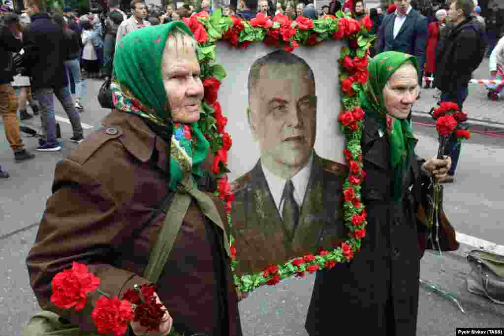 Galina Shkura (left) and Mariya Shkura -- both World War II veterans -- carry a portrait of Chief Marshal Georgiy Zhukov, a symbol of the Soviet Union&#39;s victory over Nazi Germany in World War II, as they celebrate Victory Day in Kyiv on May 9. (TASS/Pyotr Sivkov)
