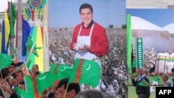 Residents walk past a poster of Turkmen President Gurbanguly Berdymukhammedov during an Independence Day parade in central Ashgabat in October 2008