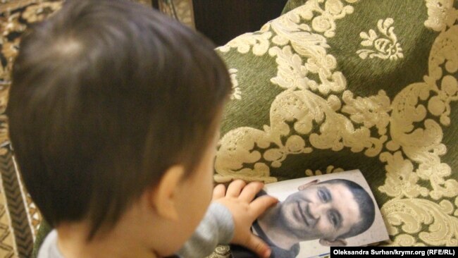 Младший сын Абхаировых, Эмир, рассматривает фото отца