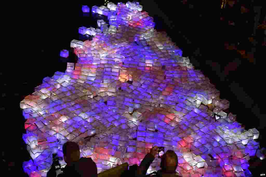 People take photos of lanterns set afloat in the Canal Saint-Martin in Paris on November 13 during a ceremony dedicated to victims of the Paris terror attacks a year before. (AFP/Alain Jocard)