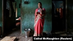 Мать девочки, убитой семьей ее мужа в индийском штате Уттар-Прадеш, с ее фотографией. 