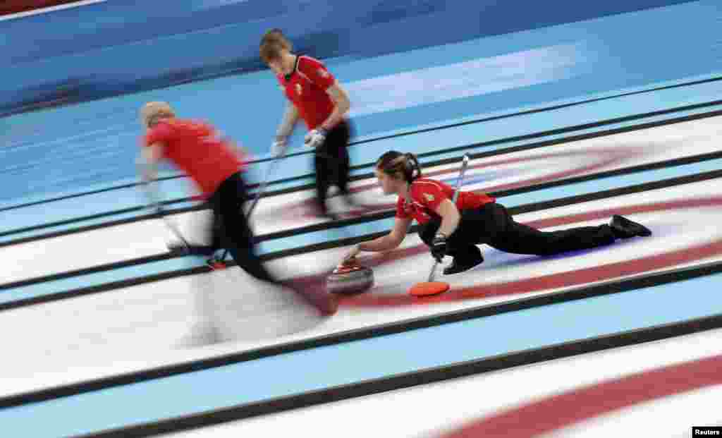 Britain's Vicki Adams (right) delivers a stone as Anna Sloan and lead Claire Hamilton prepare to sweep ahead of it during their women's curling bronze-medal game. (Reuters/Phil Noble)