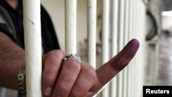 A prison inmate shows his ink-stained finger after voting early inside a prison in Irbil today.