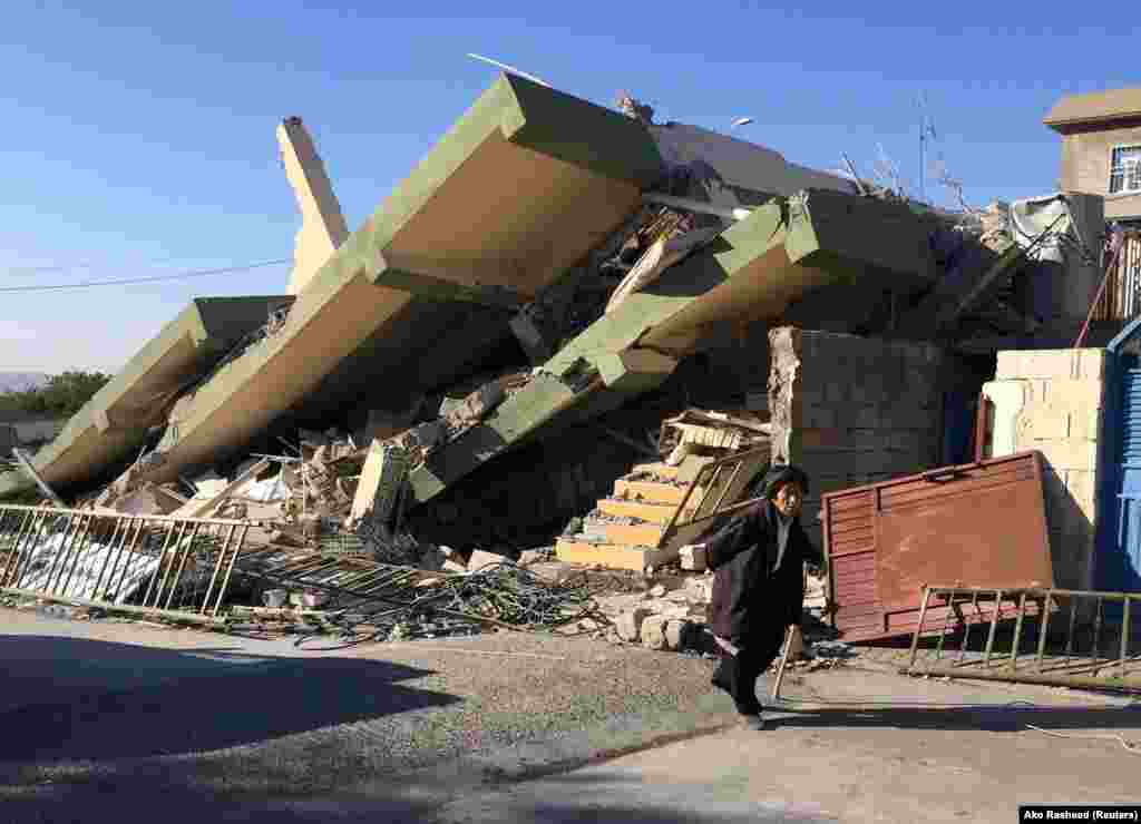 A man walks past a damaged building in Darbandikhan in Sulaimaniya Governorate, Iraq.