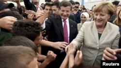 Turkey -- Turkish Prime Minister Davutoglu and German Chancellor Merkel are greeted by refugees in Nizip refugee camp, 23April2016
