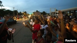 US -- People line up in the street during a peaceful demonstration, as communities react to the shooting of Michael Brown in Ferguson, Missouri August 14, 2014. 