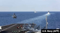 The aircraft carrier USS Abraham Lincoln transits the Strait of Hormuz as an MH-60S Sea Hawk helicopter lifts off from the flight deck, November 19, 2019