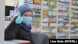 Un copil cu mască și mănuși de protecție își așteaptă părinții la o farmacie din Chișinău. 19 martie 2020