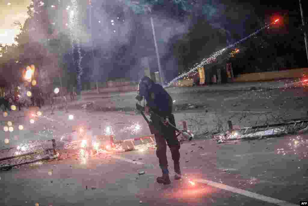 Egyptian students who support the Muslim Brotherhood shoot fireworks at a policemen (foreground) during clashes outside the University of Cairo campus on December 11. (AFP/Mahmoud Khaled)