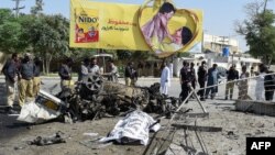 A body is covered at the site of an explosion that targeted a police vehicle in Quetta on June 23. Thirteen people were killed.