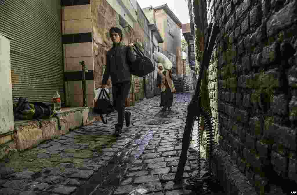 People walk past a rifle leaning against a wall as they leave their houses during heavy clashes between Kurdish militants and government forces in Diyarbakir, Turkey, on November 6. &nbsp;(AFP/Ilyas Akengin)