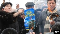 Лидеры и активисты партии ОСДП жгут плакаты президентской партии "Нур Отан". Алматы, 17 января 2012 года.