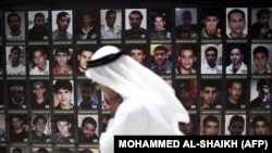 Bahrain -- A Bahraini man walks past portraits of men reportedly detained after attending anti-government protests, displayed behind a mosque in the village of Diraz, west of Manama, on July 10, 2015. AFP PHOTO / MOHAMMED AL-SHAIKH / AFP PHOTO / MOHAMMED