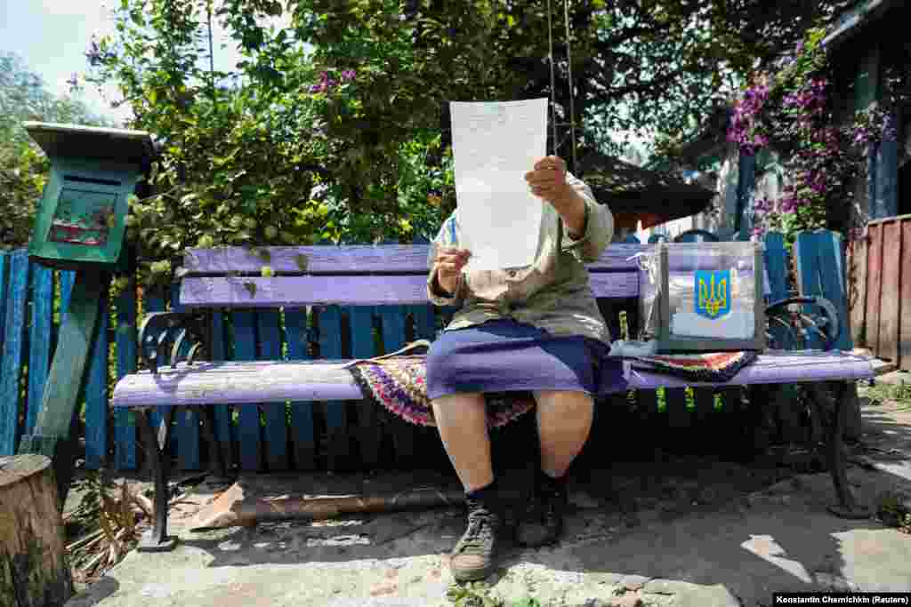 Жанчына праглядае бюлетэнь перад укідваньнем яго ў мабільную скрыню для галасаваньня падчас парлямэнцкіх выбараў у Кіеўскай вобласьці Ўкраіны 21 ліпеня.