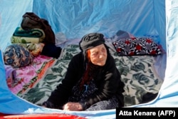 An Iranian woman looks out from a tent pitched near damaged buildings in the town of Sarpol-e Zahab in Kermanshah Province on November 14.