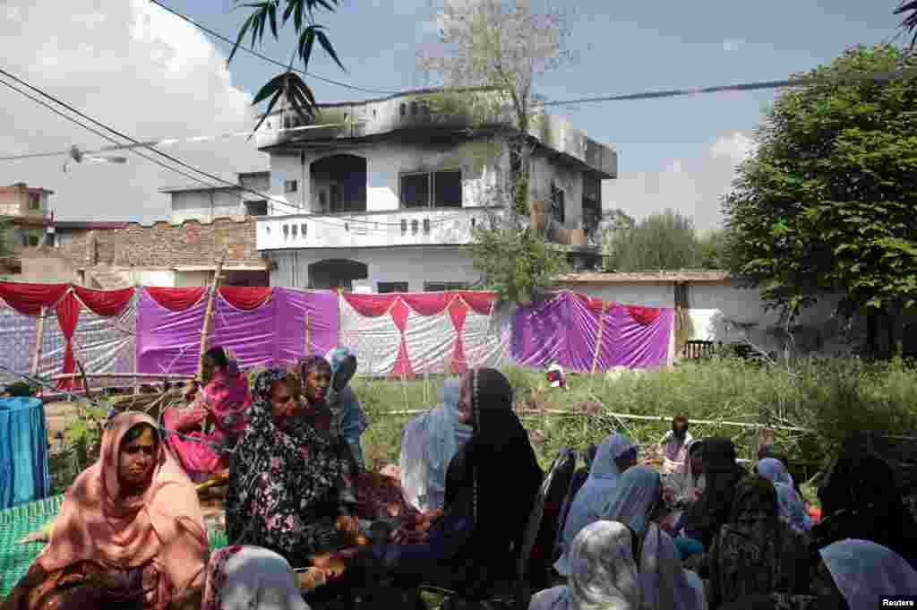 Women and children sit near a damaged building after a military aircraft on a training flight crashed in the garrison city of Rawalpindi, Pakistan. At least 18 people were killed -- 13 civilians and five crew members. (Reuters/Saiyna Bashir)