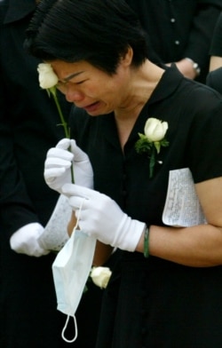 Женщина, оплакивающая медика в Гонконге, который заболел SARS и скончался в мае 2003 года после того, как вирус, вышедший из отеля Metropole, распространился на территории Гонконга.
