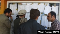 Afghan election observers check the voting results put on display at a polling center after ballots in the country's legislative election were counted in Kabul on October 22. 