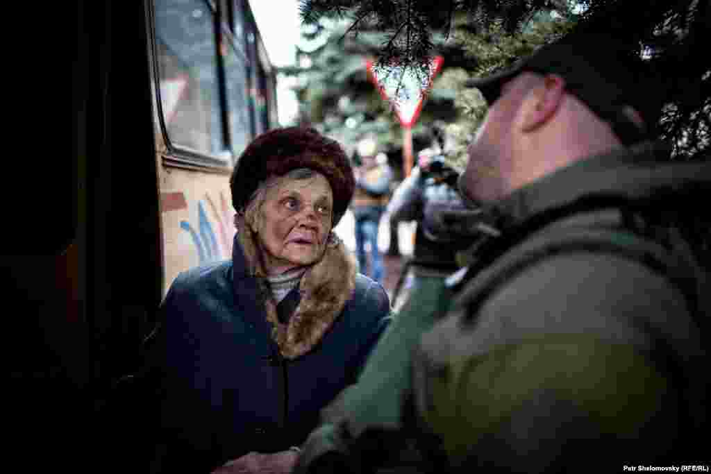 A Ukrainian army officer helps an elderly woman onto a bus leaving Debaltseve.