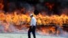 Iran -- An Iranian policeman walks past a cloud of smoke rising from a pile of drugs set on fire during an incineration ceremony of some 50 tons of illicit drugs in an annual ritual in Tehran, June 26, 2014