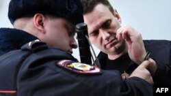 A Russian policeman removes handcuffs from Kremlin critic Aleksei Navalny after he was arrested during a March 2017 anti-corruption rally in Moscow.