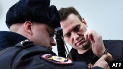 A Russian policeman removes handcuffs from Kremlin critic Aleksei Navalny, who was arrested during a March 26 anticorruption rally, during an appeal hearing at a court in Moscow on March 30.